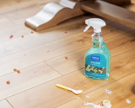 Durable and easy-to-clean luxury vinyl plank flooring in a residential setting Luxury vinyl plank flooring with cleaning spray and scattered food debris