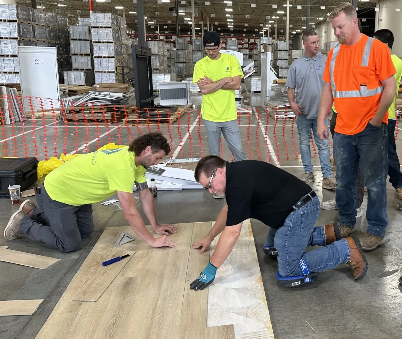 Group of workers installing light wood flooring in a warehouse setting