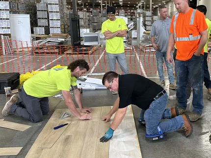 Warehouse Flooring Installation with Light Wood Planks Group of workers installing light wood flooring in a warehouse setting