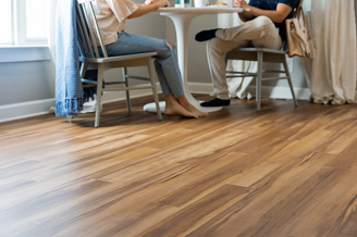 A couple enjoying a meal together at a cozy table in a room with luxury vinyl flooring.