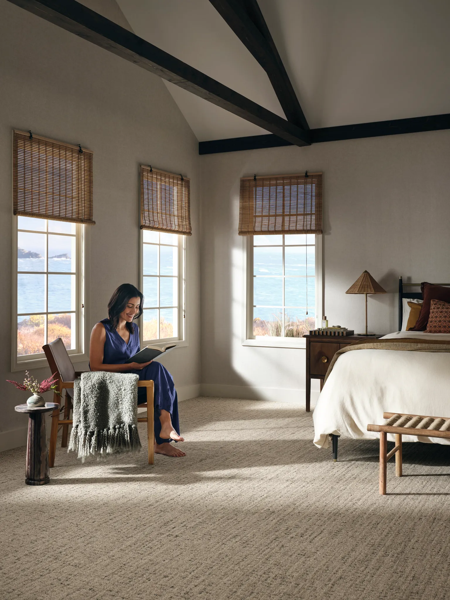 Outdoor patio with terracotta roof tiles and white walls, featuring a wooden bench with orange striped cushions and a light gray blanket