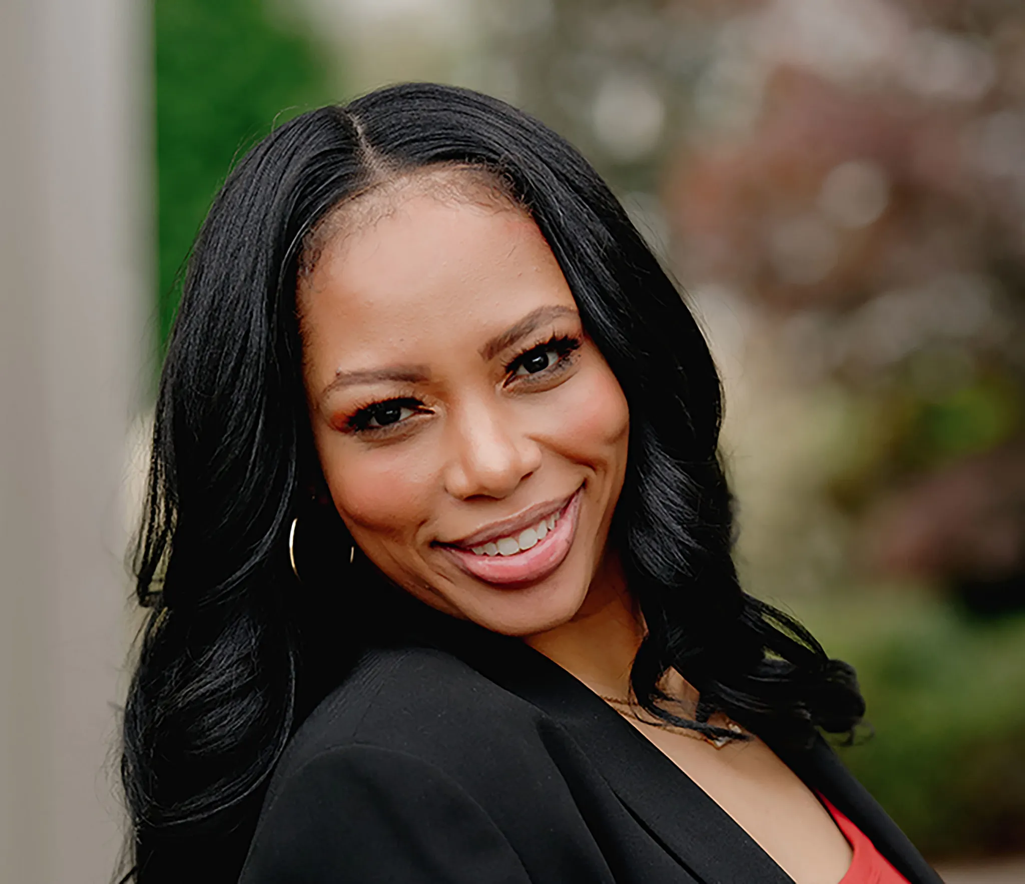 Professional woman in a black blazer standing outdoors with blurred background