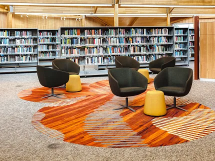 University of Tasmania Library Featuring Custom Flooring Design | Shaw Contract Custom flooring installation within the University of Tasmania library featuring organic patterns inspired by Indigenous storytelling, alongside collaborative seating and book collections.