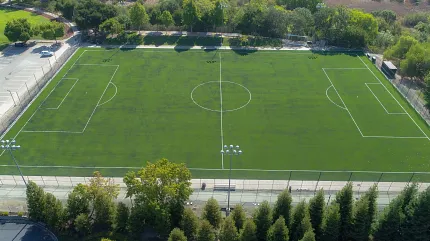 Artificial Turf Soccer Field Aerial View Aerial view of a large artificial turf soccer field surrounded by trees and a parking lot