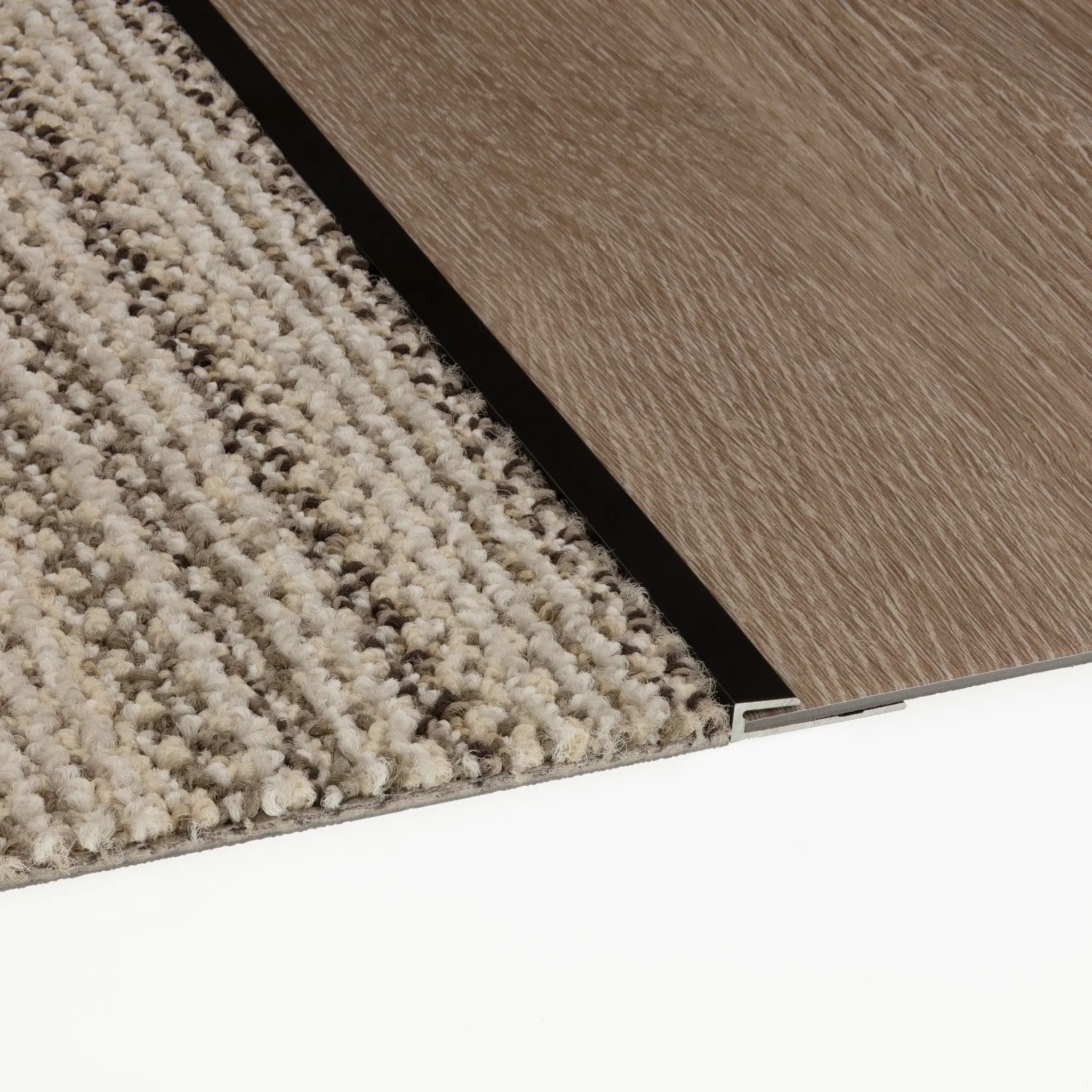Close-up of commercial carpet tile in beige and brown tones transitioning to wood-look commercial LVT flooring