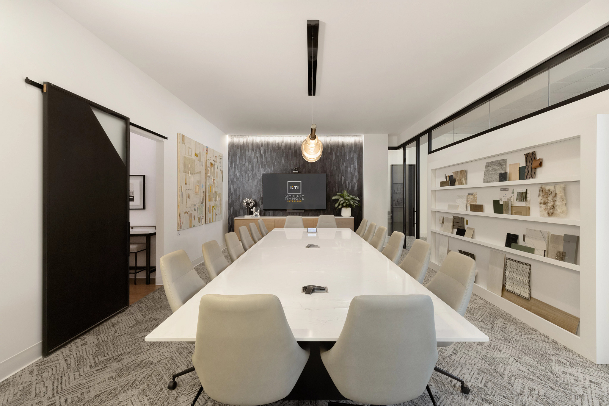 Modern conference room with a long white table, beige chairs, and patterned commercial carpet tile flooring