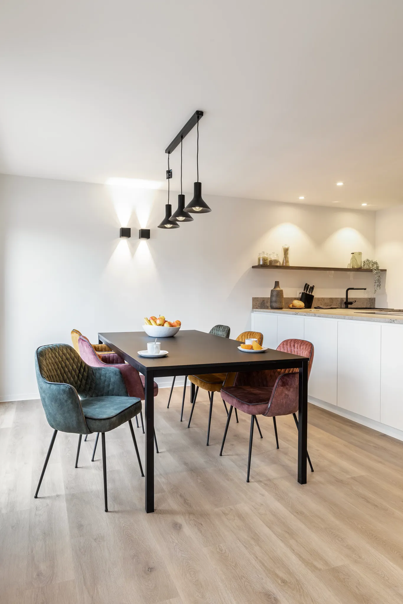 Modern dining room with colourful chairs and light wooden plank floors from Coretec
