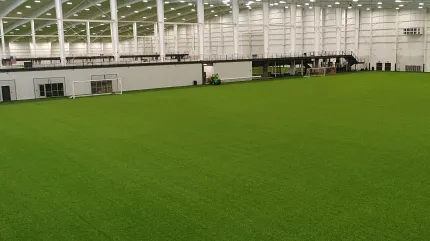 Spacious indoor field with synthetic grass flooring Indoor sports facility with green artificial turf