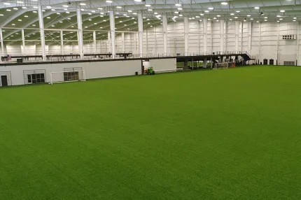 Spacious indoor field with synthetic grass flooring Indoor sports facility with green artificial turf