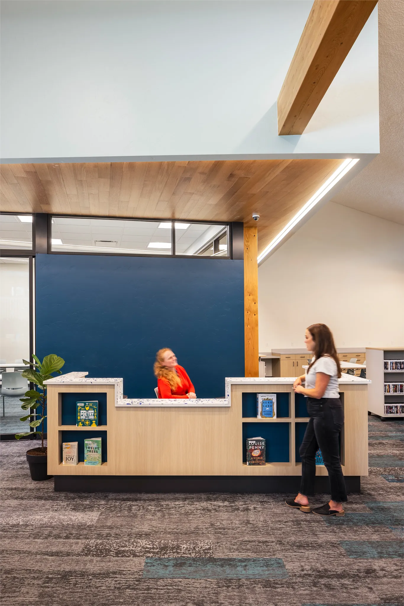Education facility with commercial carpet tile flooring in shades of gray and blue, featuring a wooden reception desk and bookshelves