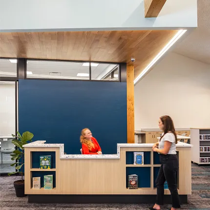 Education Facility with Commercial Carpet Tile Flooring and Wooden Reception Desk Education facility with commercial carpet tile flooring in shades of gray and blue, featuring a wooden reception desk and bookshelves