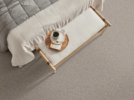 Comfortable and Durable Beige Carpet for a Cozy Bedroom Ambiance Cozy bedroom scene with a soft, textured carpet in a neutral beige tone, featuring a neatly made bed with a gray quilt and a wooden bench with a breakfast tray
