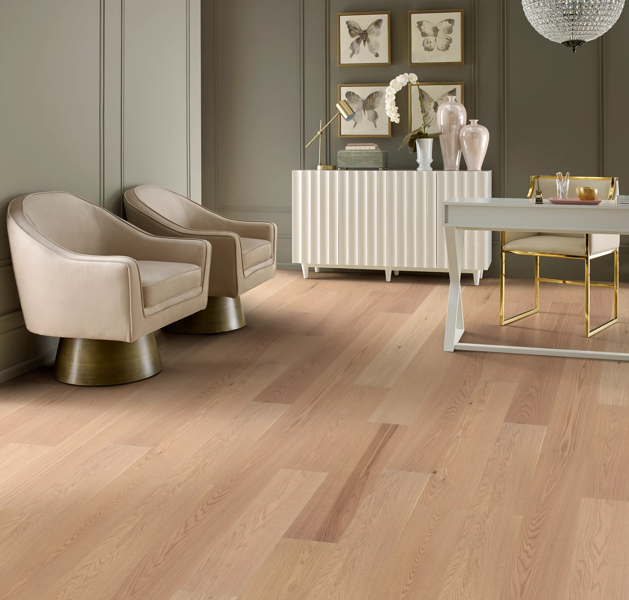 Elegant living room with light wood flooring, featuring beige armchairs, a white sideboard, and decorative elements