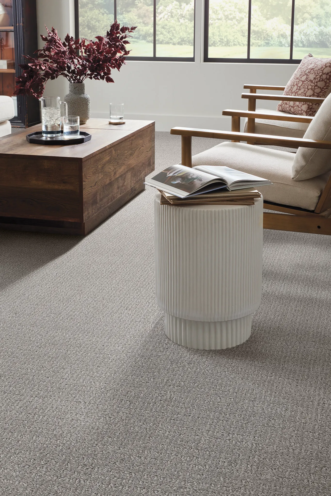 Cozy living room with textured gray carpet, wooden coffee table, and modern white side table