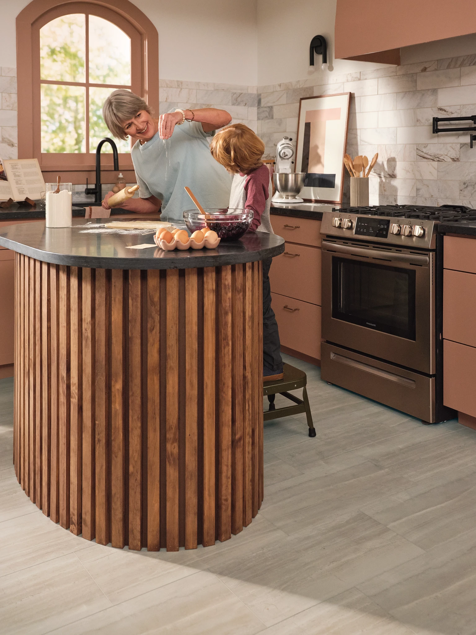 kitchen with floor in a light stone look with a wooden island and stainless steel appliances