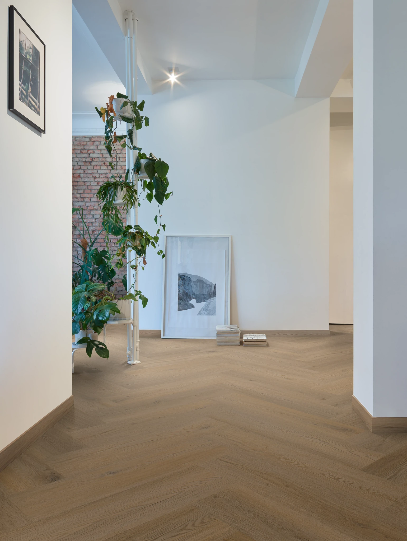 living room with wood look luxury vinyl plank floor in a herringbone pattern with a decor with plants and artwork