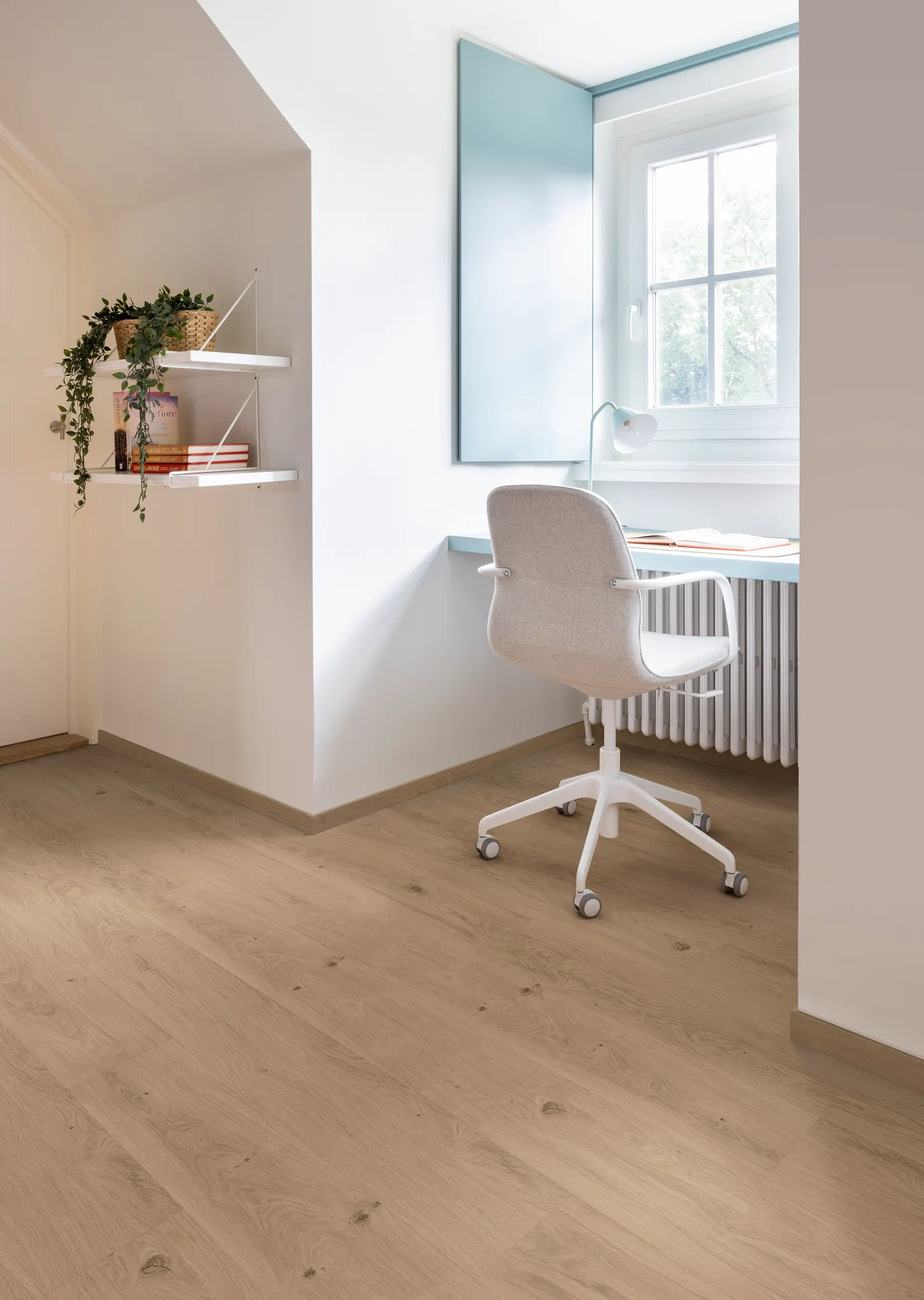 Modern home office with light oak wood look luxury vinyl plank flooring, white swivel chair, and minimalist decor