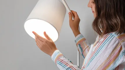 Modern white lamp being adjusted by a woman in a home environment Woman adjusting a modern white lamp in a residential setting
