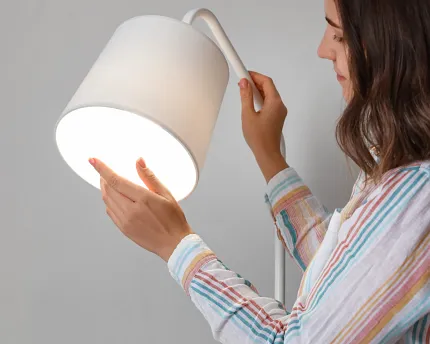 Modern white lamp being adjusted by a woman in a home environment Woman adjusting a modern white lamp in a residential setting