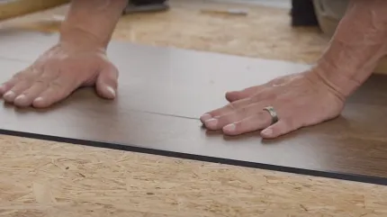 Commercial LVT Flooring Installation Process Hands installing commercial LVT flooring on plywood subfloor