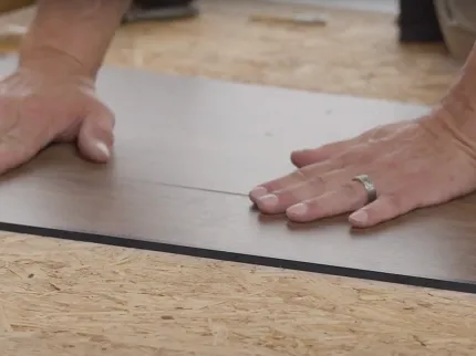 Commercial LVT Flooring Installation Process Hands installing commercial LVT flooring on plywood subfloor