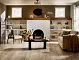 <h2 class="text-bodycopy-l"><span style="color:#ffffff;"><strong>Need Design Help?</strong></span></h2>
Cozy living room with SPC flooring in natural wood tones, featuring a white brick fireplace, comfortable seating, and decorative elements