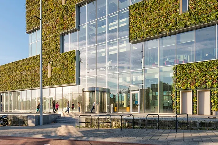 Modern education facility exterior with green wall and glass facade
