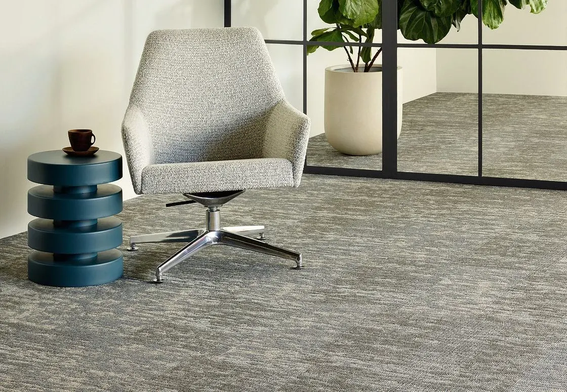Modern office space with gray commercial carpet tile, featuring a contemporary chair and side table