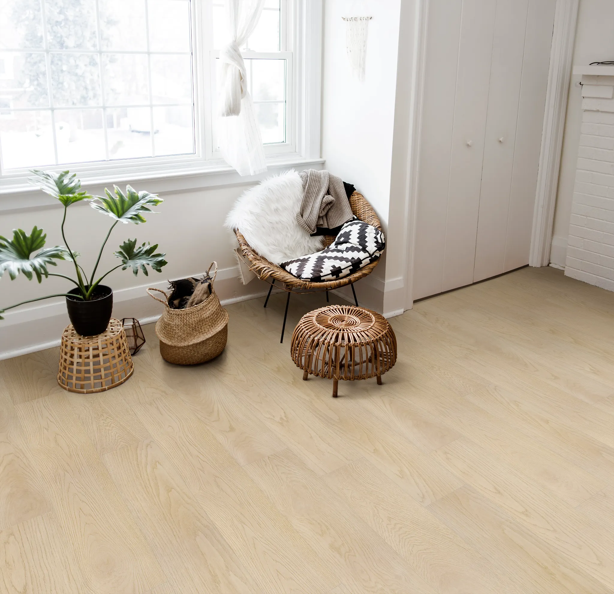 living room with light wood SPC floor with a wicker chair with a black and white cushion a fluffy throw and a potted plant