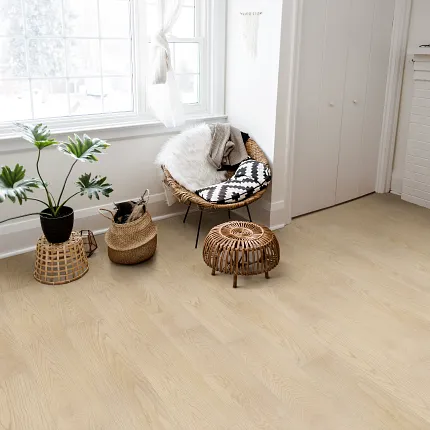 Light Wood SPC Flooring in Cozy Living Room - 59.06x8.86 inch living room with light wood SPC floor with a wicker chair with a black and white cushion a fluffy throw and a potted plant