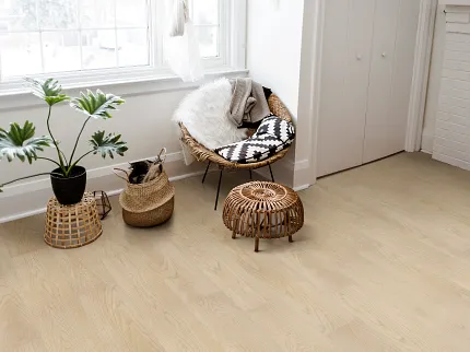 Light Wood SPC Flooring in Cozy Living Room - 59.06x8.86 inch living room with light wood SPC floor with a wicker chair with a black and white cushion a fluffy throw and a potted plant