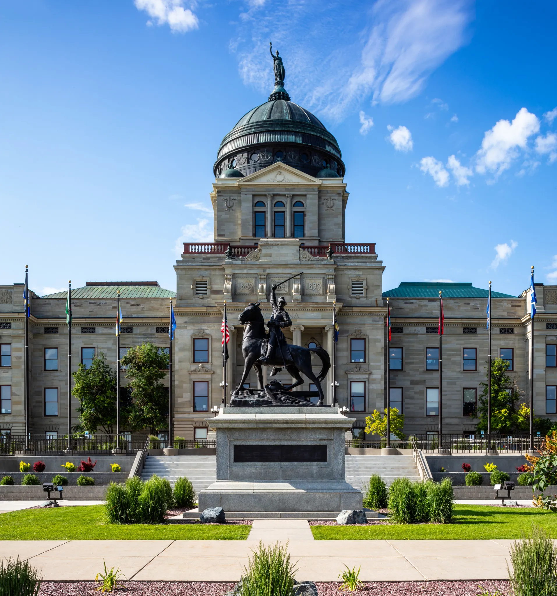 Government building with statue and flags under blue sky