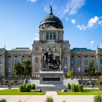 Majestic government architecture with historical monument Government building with statue and flags under blue sky
