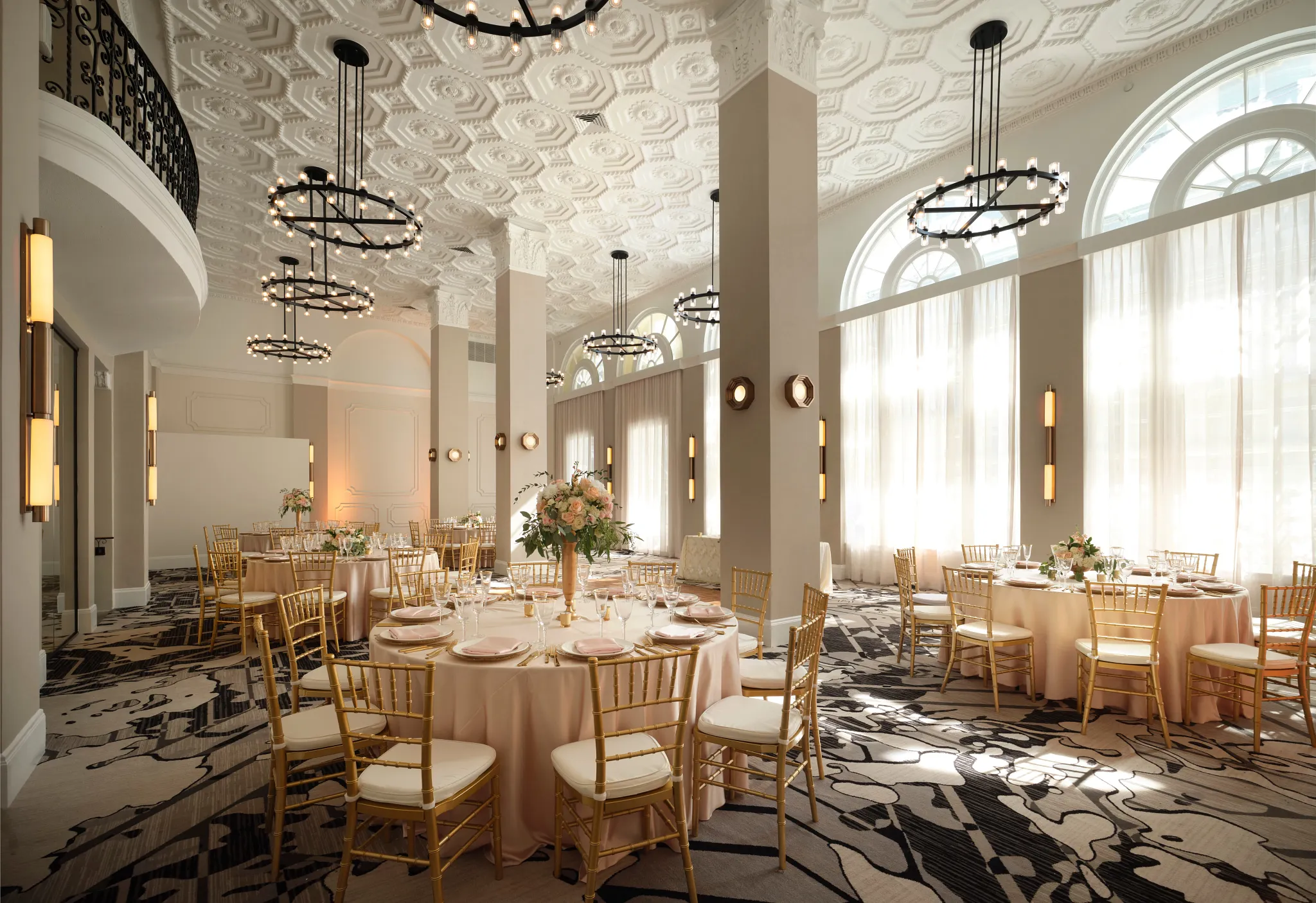 Elegant hospitality venue with round tables and gold chairs on patterned commercial carpet flooring