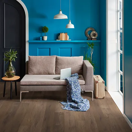 This COREtec product features Soft Step, our newest attached underlayment. living room with arched doorway, vivid blue walls a tan settee with a throw. Dark brown wood look vinyl on the floor