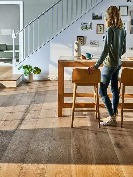 large living room with table and stairs in background woman standing at a table in a living room area