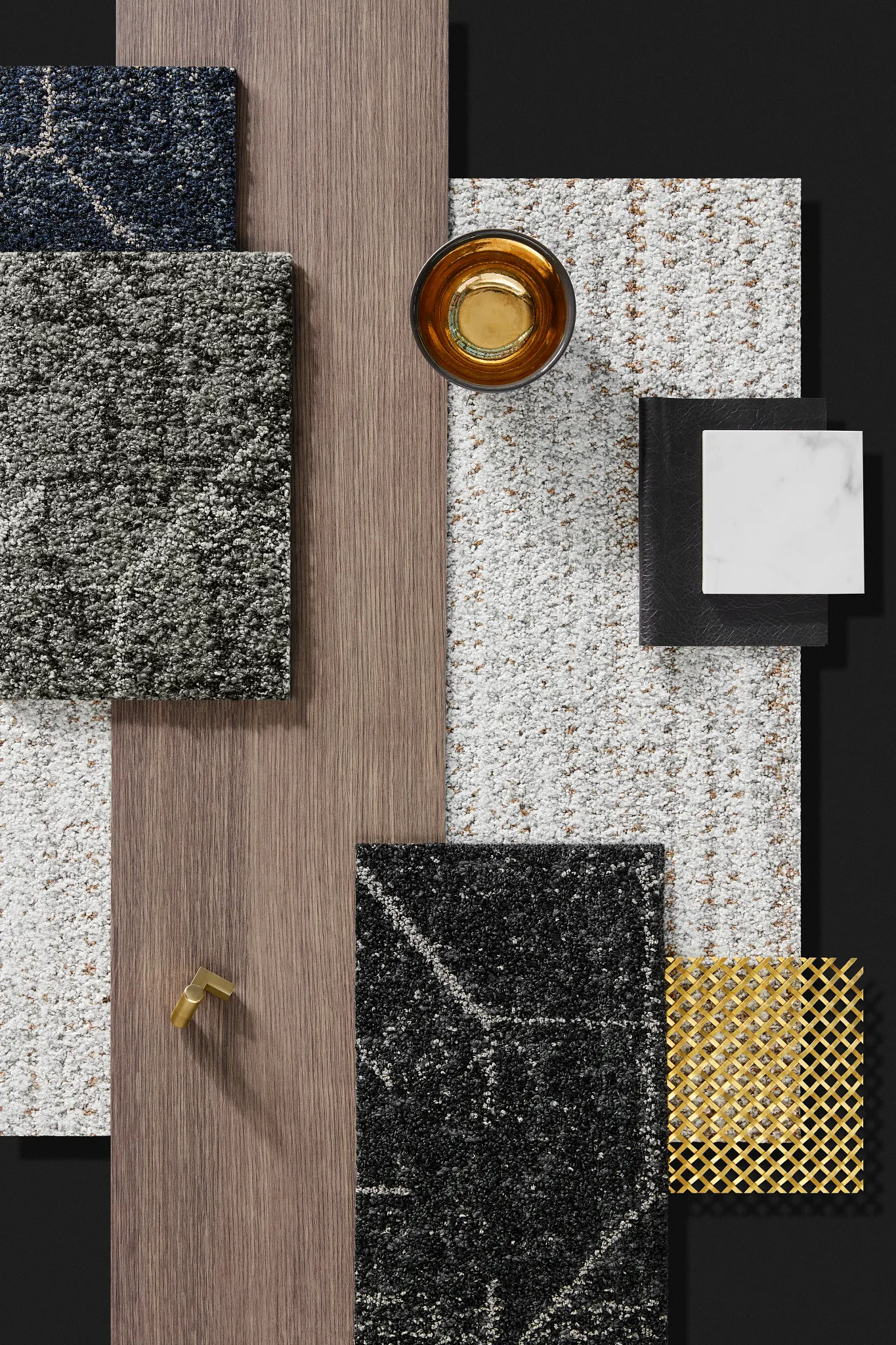 Swatch of commercial carpet tiles in blue, grey, and black with a wood plank and decorative items