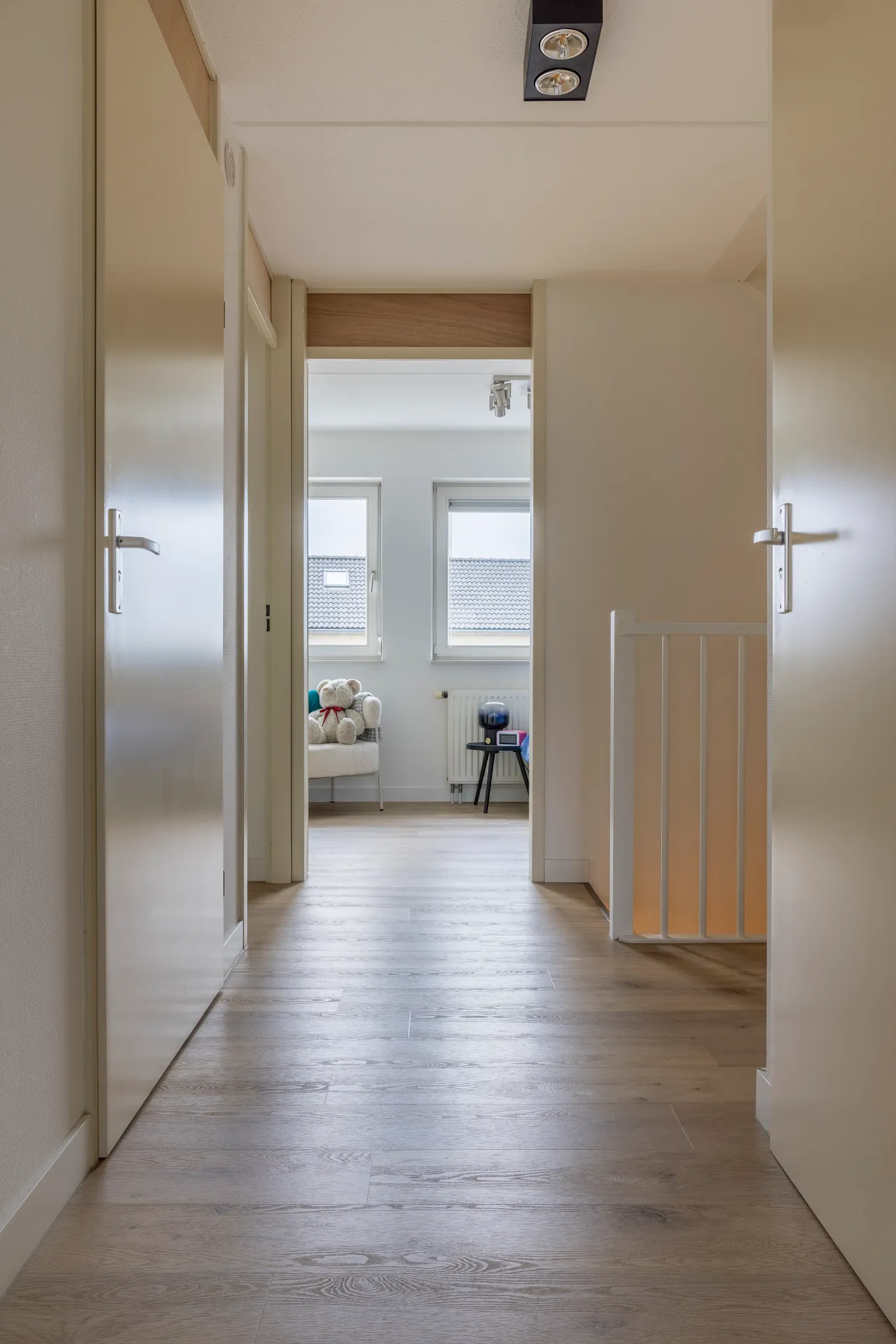 Light oak flooring in a modern hallway leading to a cozy room