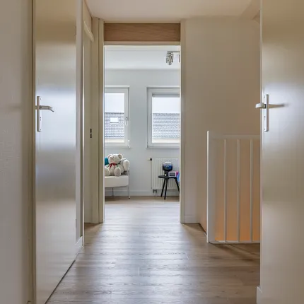 Light oak flooring in a modern hallway leading to a cozy room