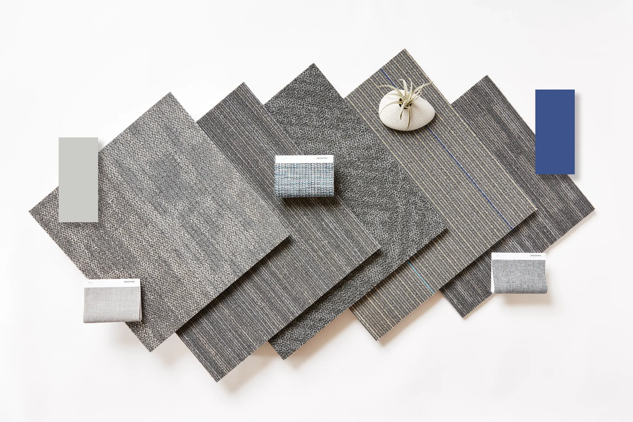 Swatch of commercial carpet tiles in various shades of gray and blue with texture details