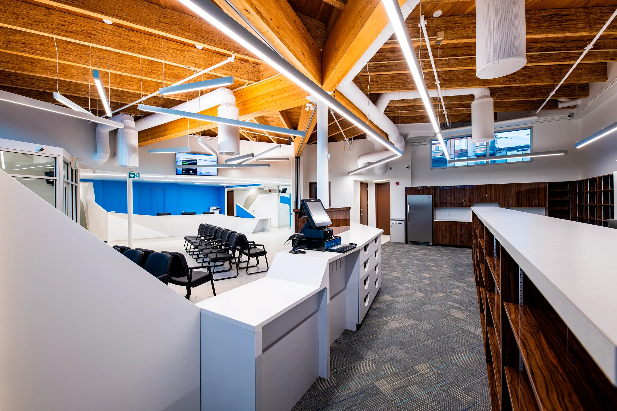 Modern retail space with commercial carpet tile flooring in a 24x24 inch size, featuring a spacious layout with wooden ceiling beams and white furniture.