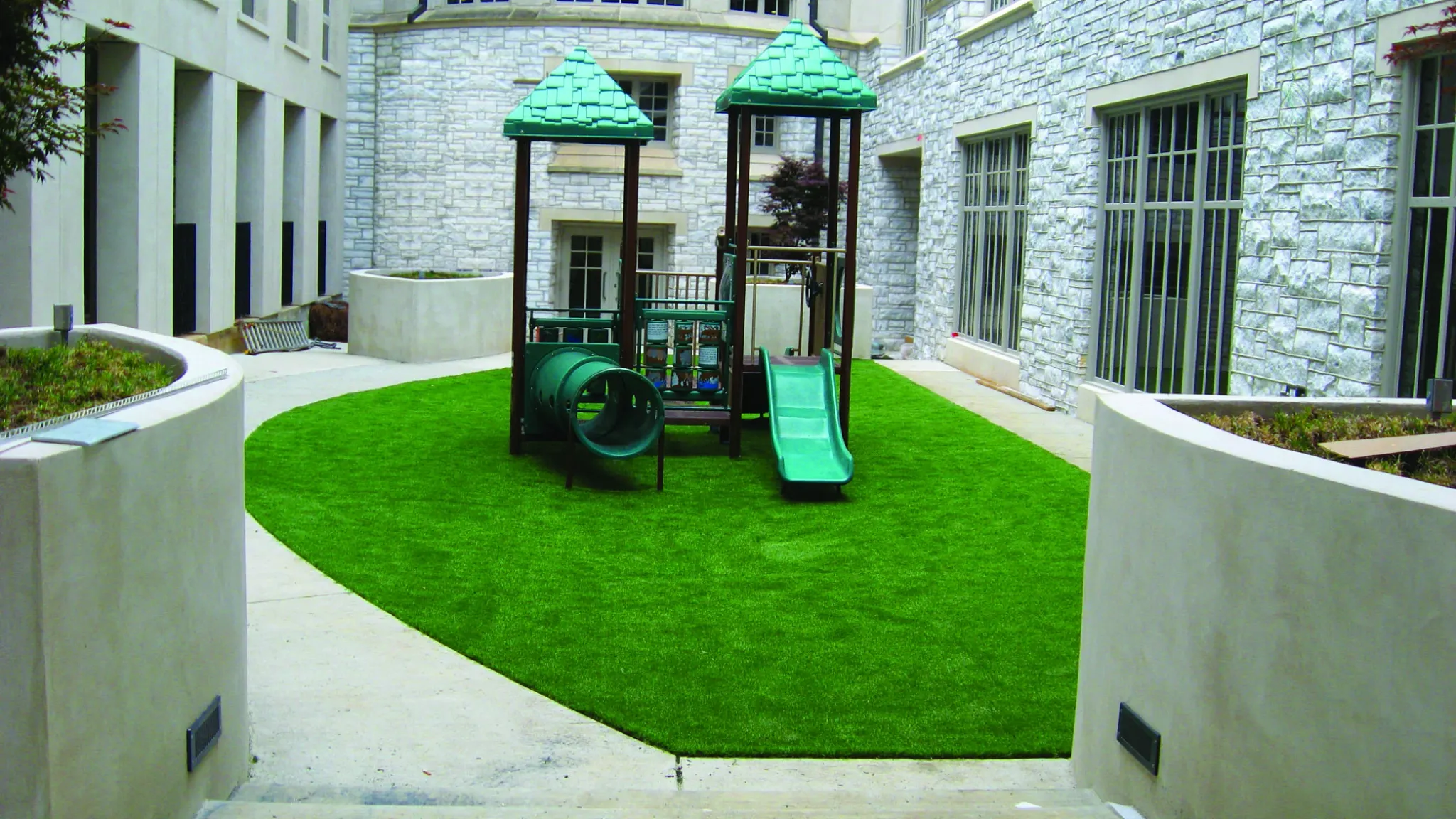 Playground with artificial grass in urban courtyard