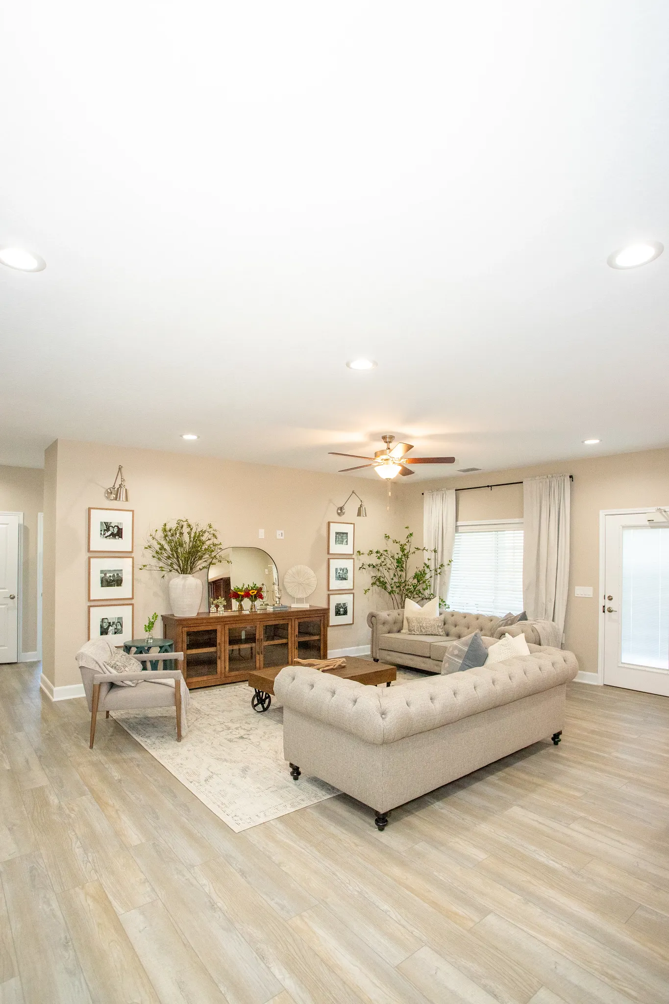 Spacious living room with beige sofas and wood-look luxury vinyl plank flooring