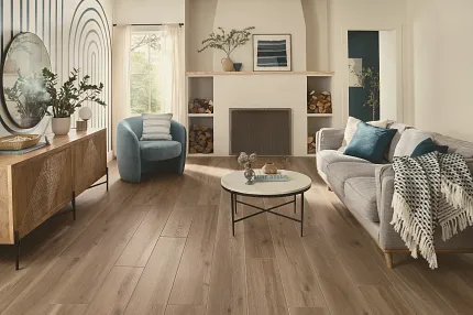 This COREtec product features Soft Step, our newest attached underlayment. large modern living room with fireplace, wood stacked on shelves, couch and large console with morror and large window, sun-filled room with light oak wood look vinyl flooring.