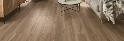 This COREtec product features Soft Step, our newest attached underlayment. large modern living room with fireplace, wood stacked on shelves, couch and large console with morror and large window, sun-filled room with light oak wood look vinyl flooring.