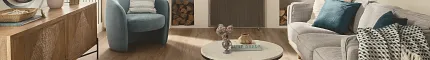 This COREtec product features Soft Step, our newest attached underlayment. large modern living room with fireplace, wood stacked on shelves, couch and large console with morror and large window, sun-filled room with light oak wood look vinyl flooring.