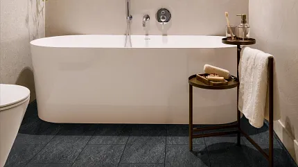 Dark Stone Look Luxury Vinyl Tile Flooring in Modern Bathroom Modern bathroom with dark stone look luxury vinyl tile flooring, featuring a white freestanding bathtub and minimalist decor.