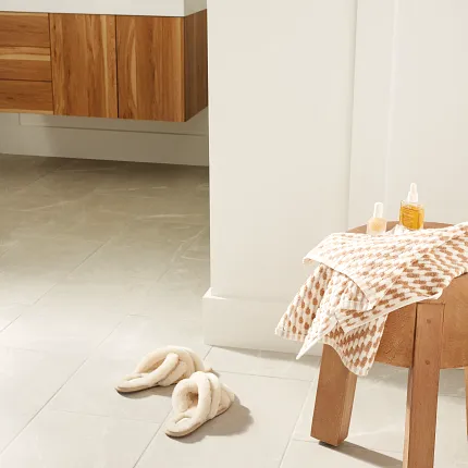 Light Beige Tile Flooring in a Cozy Modern Bathroom Setting Modern bathroom with light beige tile flooring, wooden vanity, and cozy slippers for a warm, inviting atmosphere