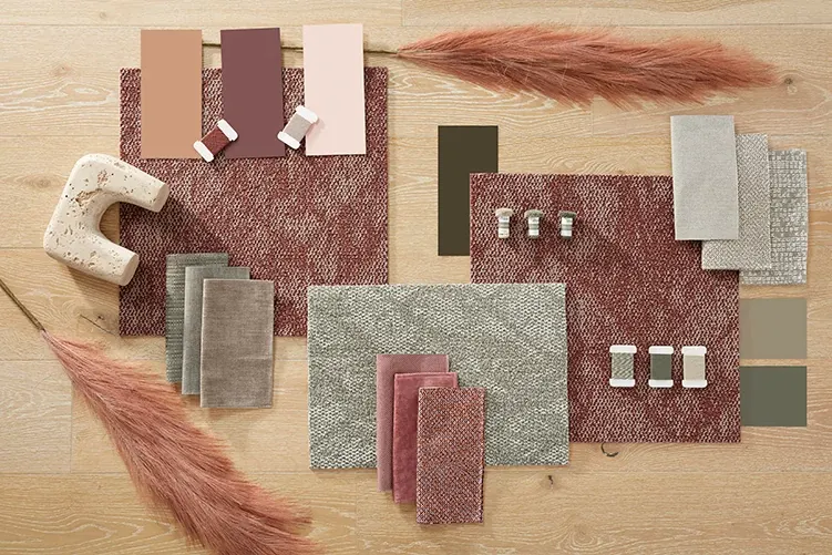 Assorted carpet swatches in shades of red, pink, and beige on a wooden floor