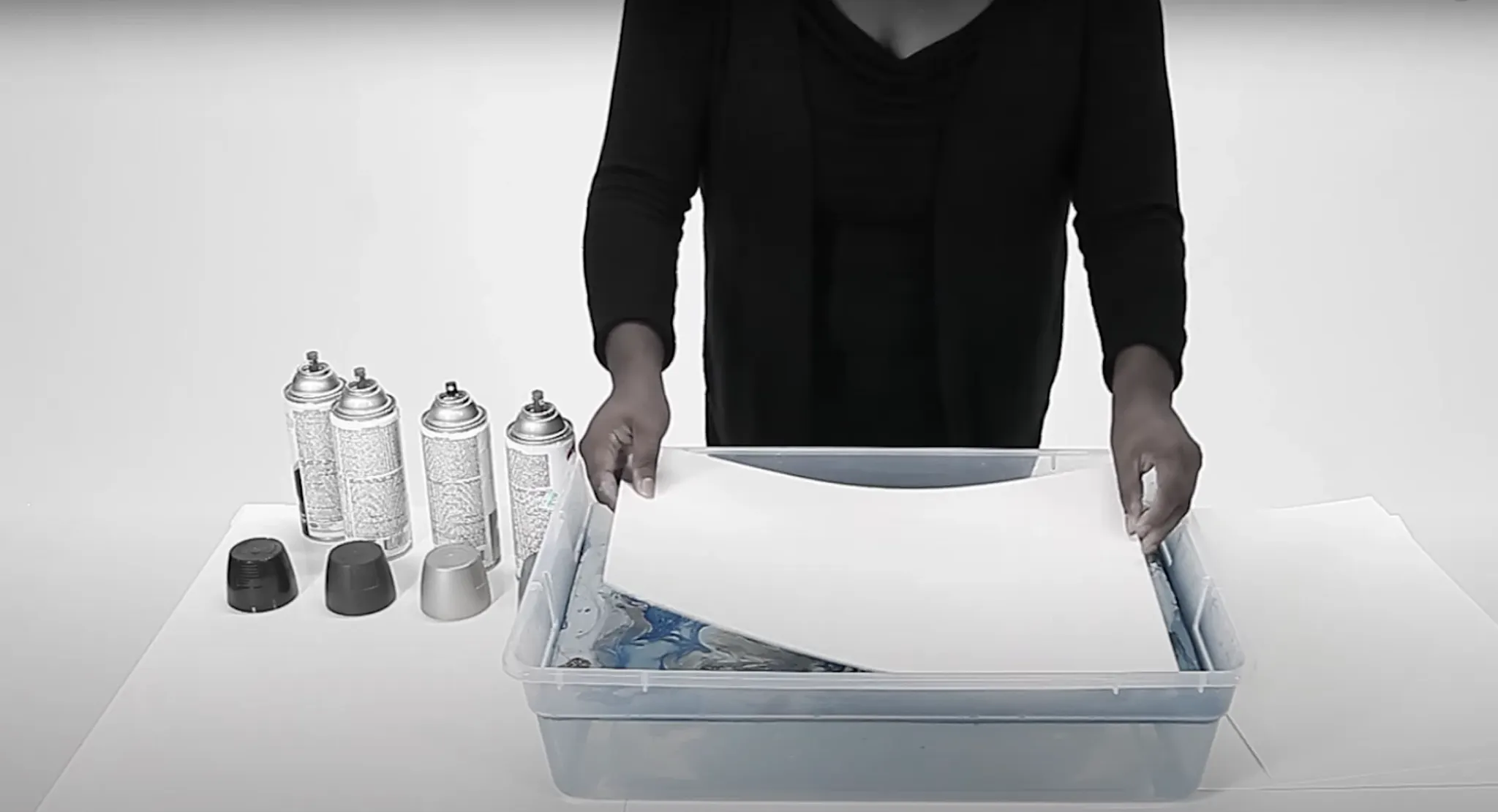 Woman preparing art materials with spray paint cans and paper in a studio setting